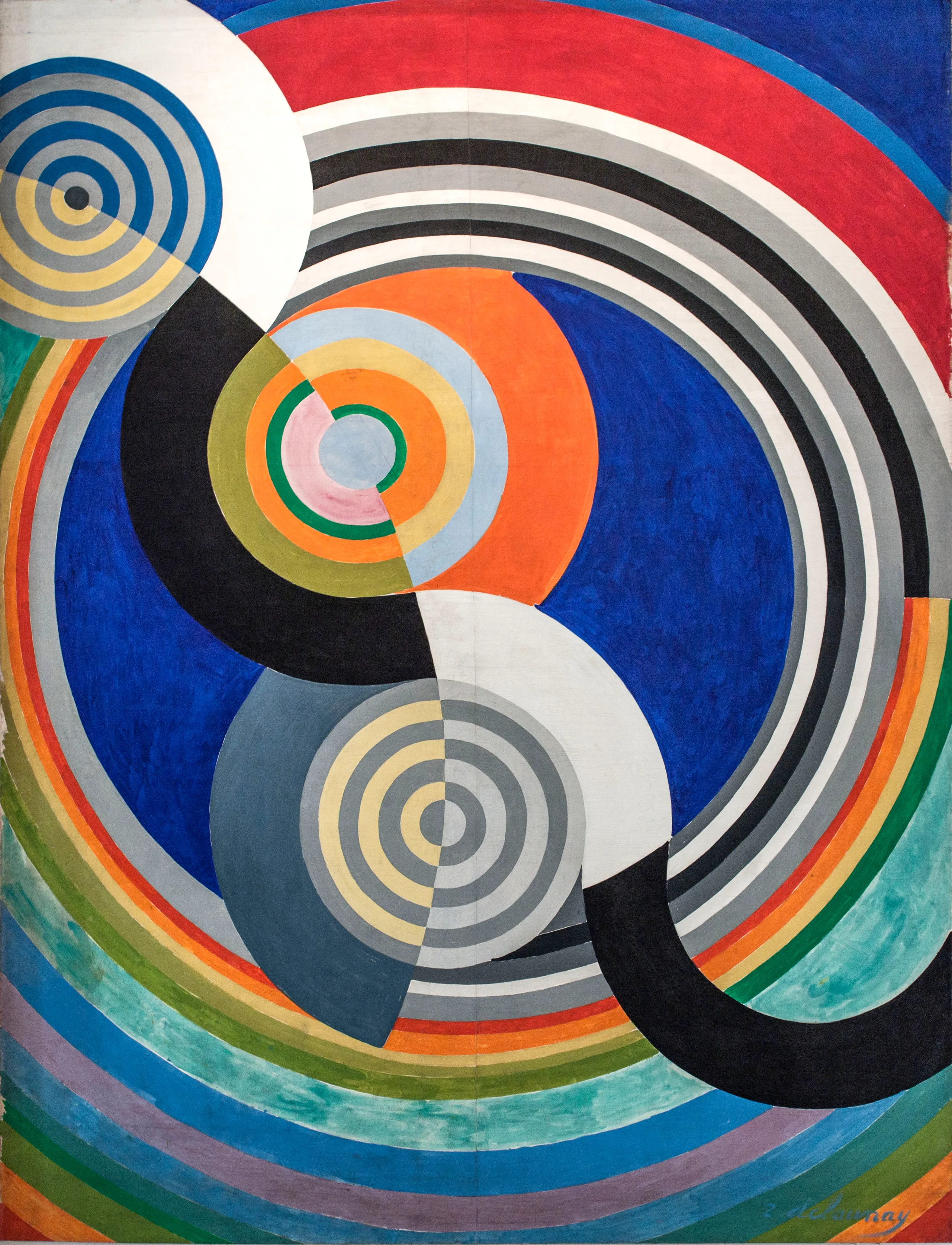 A tall panel of stacked coloured discs, arcs and rainbow bands in red, blue, yellow, green and grey on a pale ground.